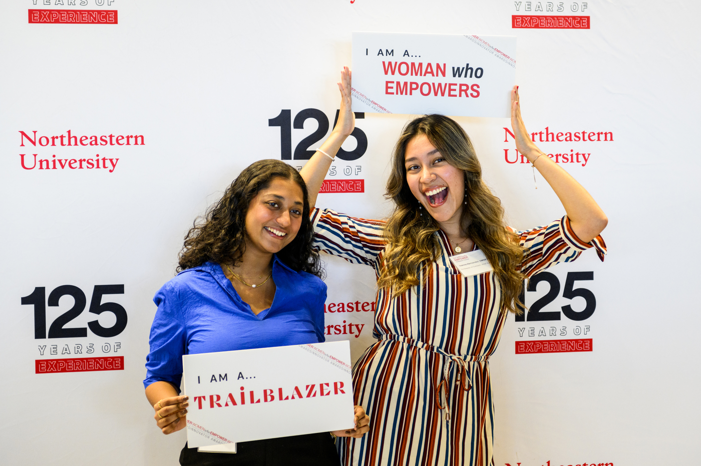 Participants pose, holding signs that say I am a Woman who Empowers