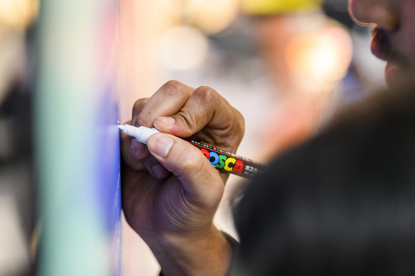 Student writing a message on the mural.