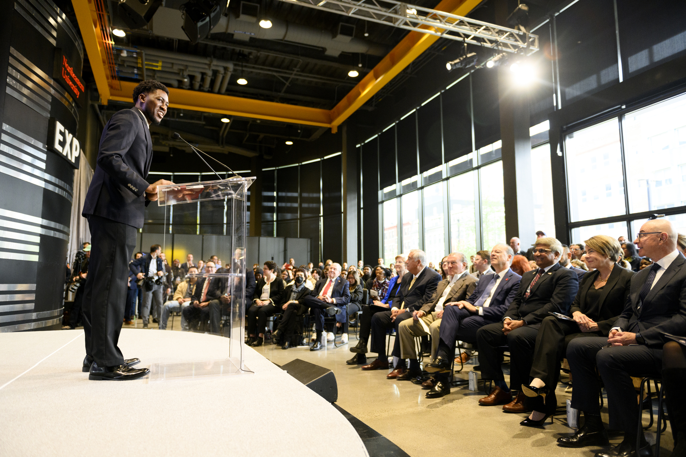 PhD student and Triple Husky James Tukpah stands on a stage.