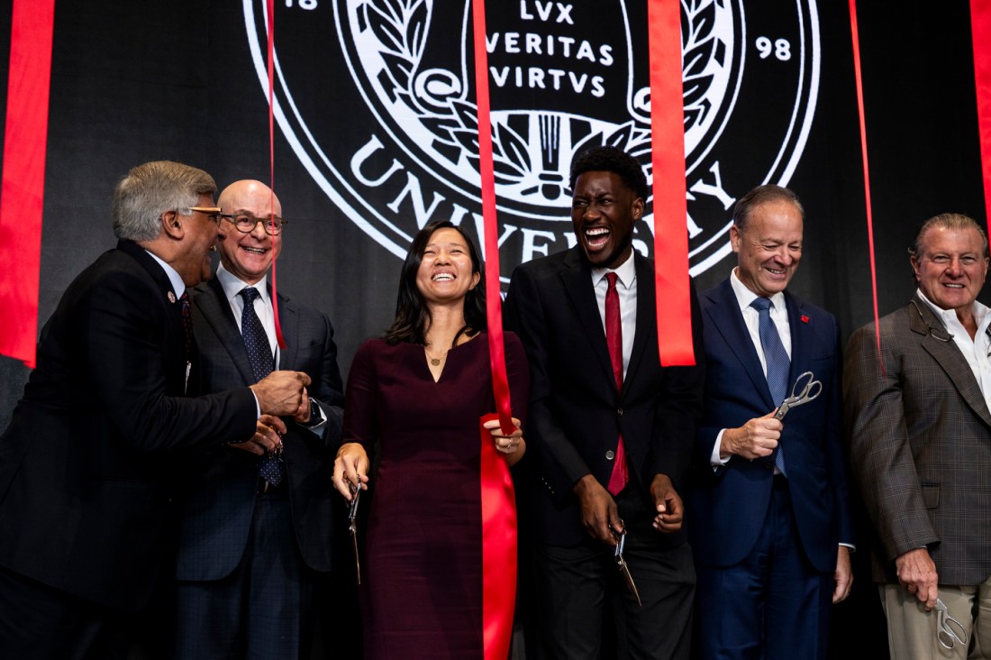 President Aoun standing on stage with other members of the Northeastern community laughing and smiling as streamers fall around them. 