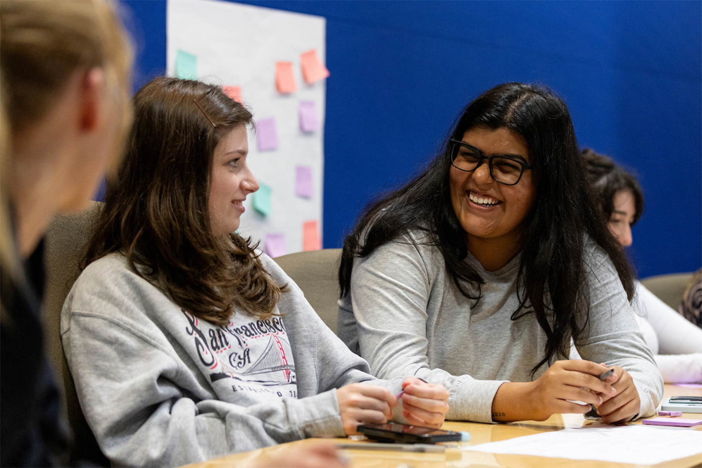 Students talking and laughing in a classroom. 