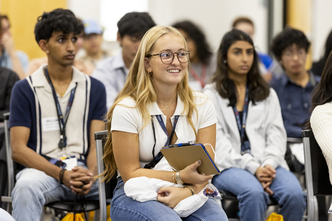 Northeastern students wearing lanyards and sitting in chairs at Northeastern's Oakland campus. 