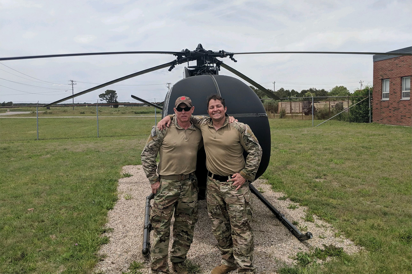 Dennis Hernandez and another military member stands outside in front of a helicopter.