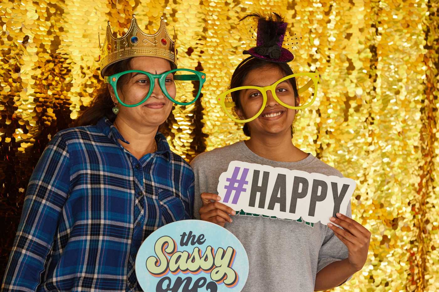 A family posing together with props in front of a gold sparkly photo background. 