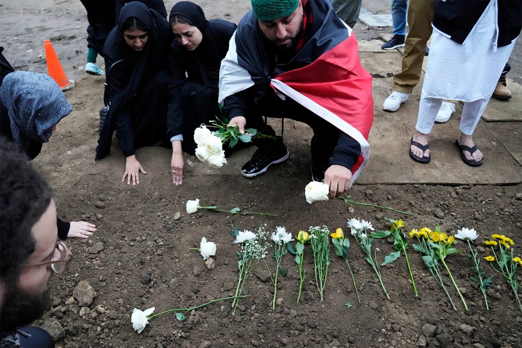 Muslim community members placing flowers on a grave.