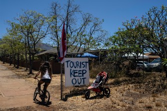 A girl riding her bike past a sign in Maui that says "Tourist Keep Out".