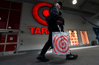 Shopper walking past a Target store carrying a plastic Target bag.