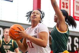 One basketball player blocking while the other looks up at the net.