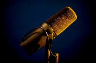 Microphone lit up by yellow light on purple background.