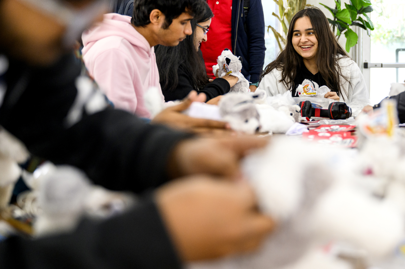 People sit around a table, stuffing husky stuffed animals.