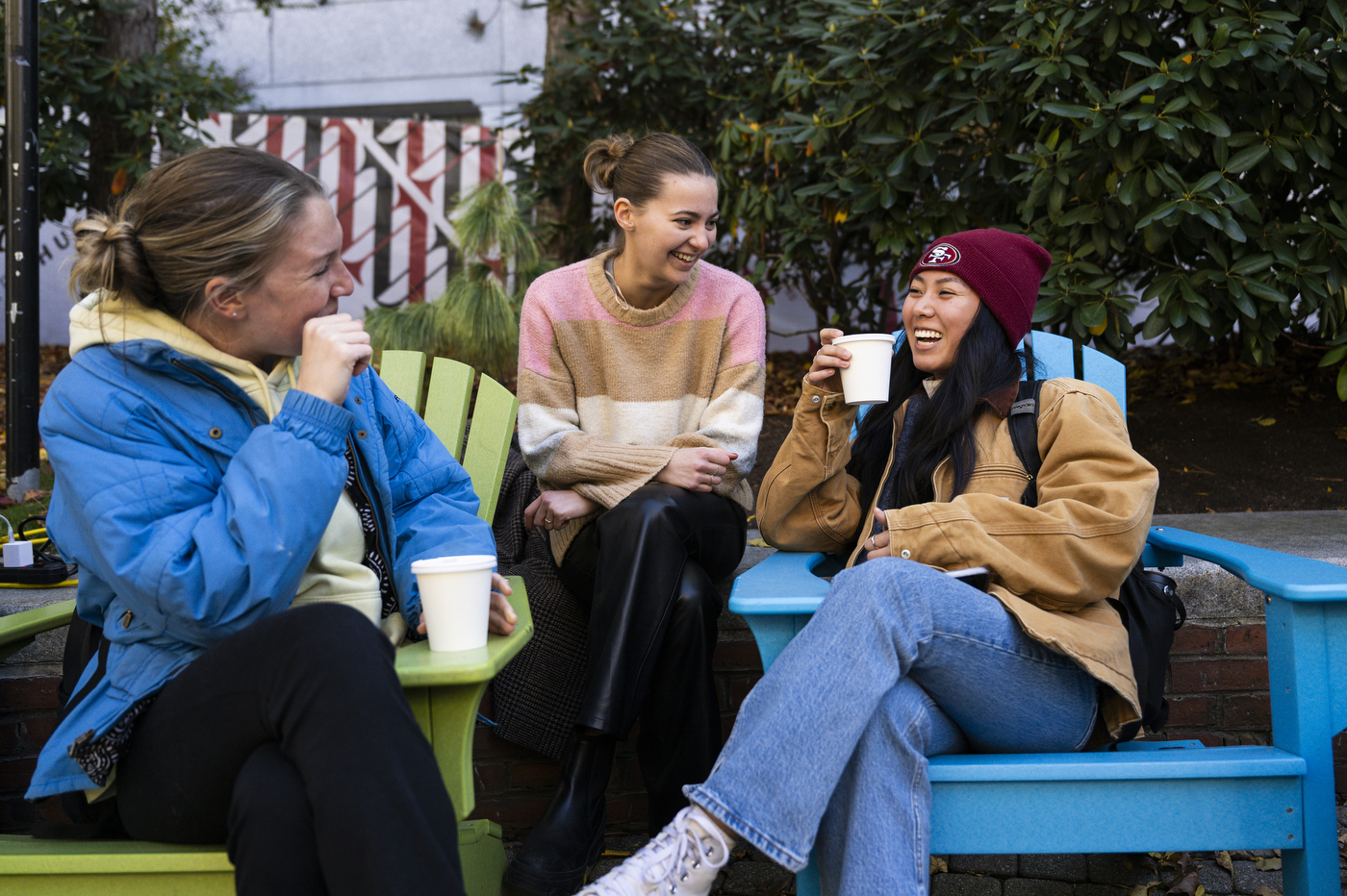 Three people sit outside while drinking apple cider.