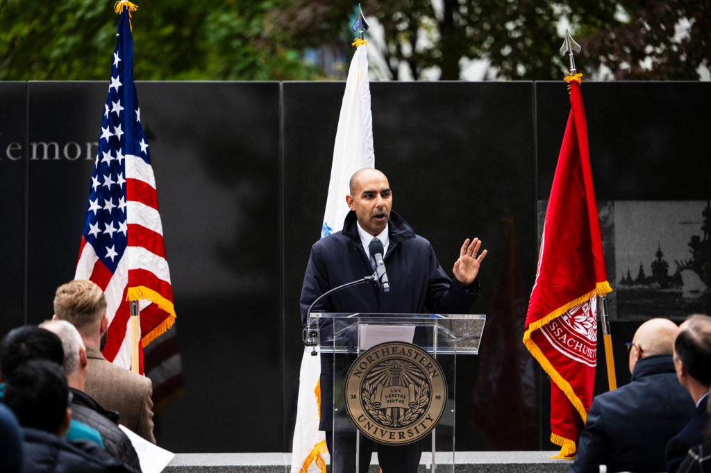 Jon Santiago speaking at a podium surrounded by flags.