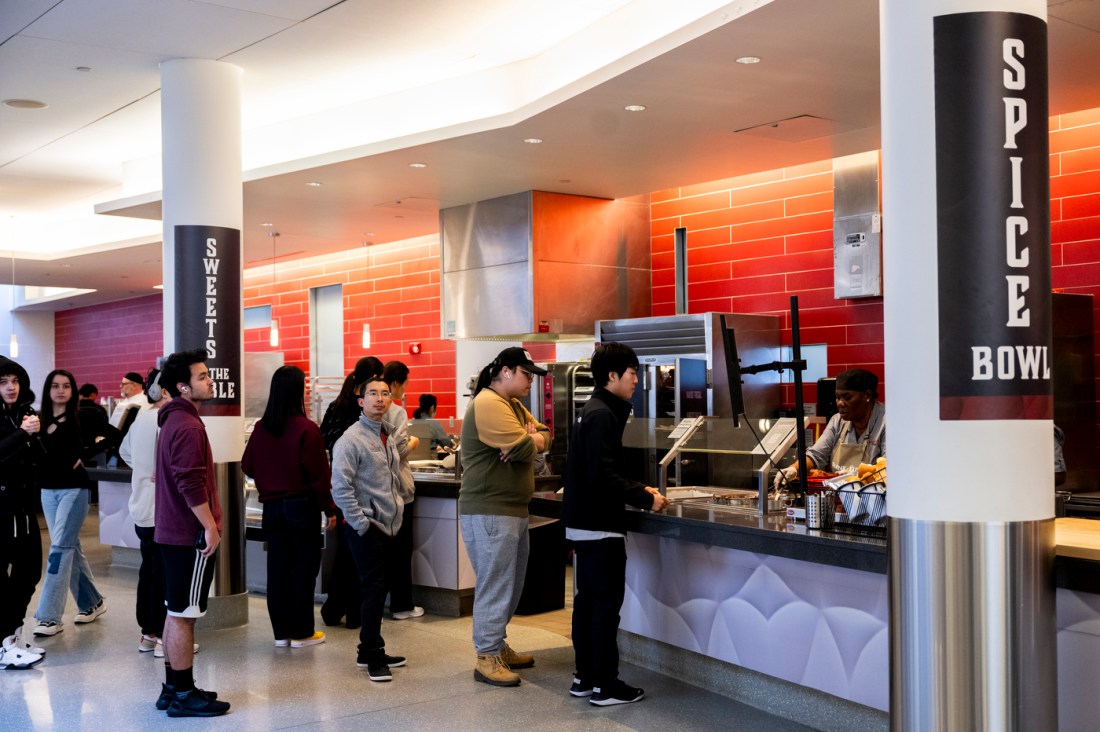 A line of students in front of a restaurant at a food court.