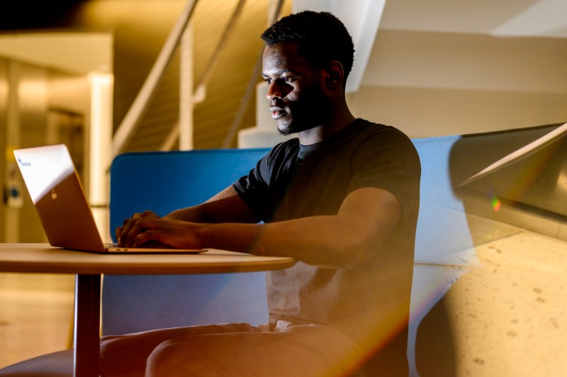 David Alade typing on his Macbook laptop.