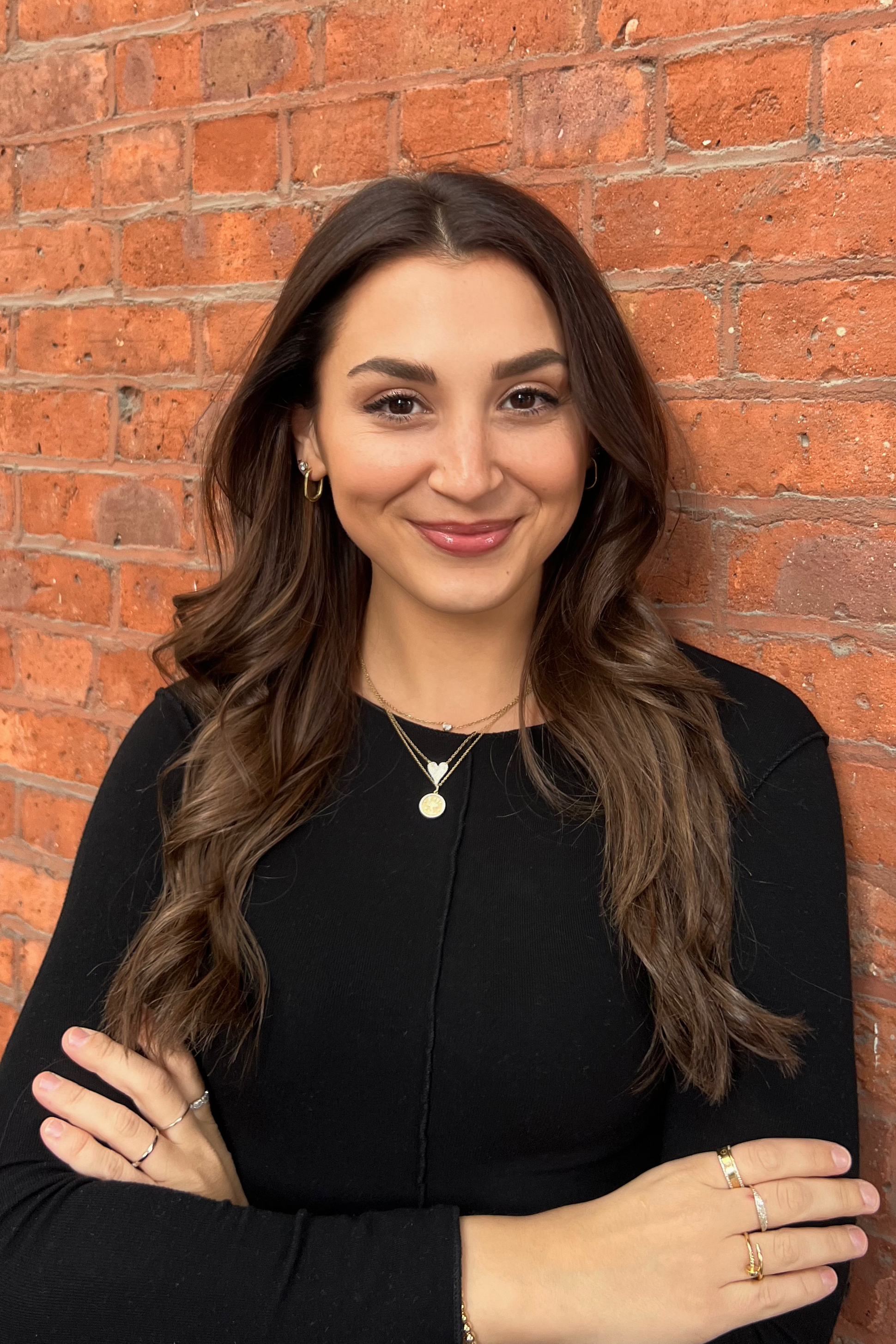 Headshot of Paige Cooper against a brick wall background.