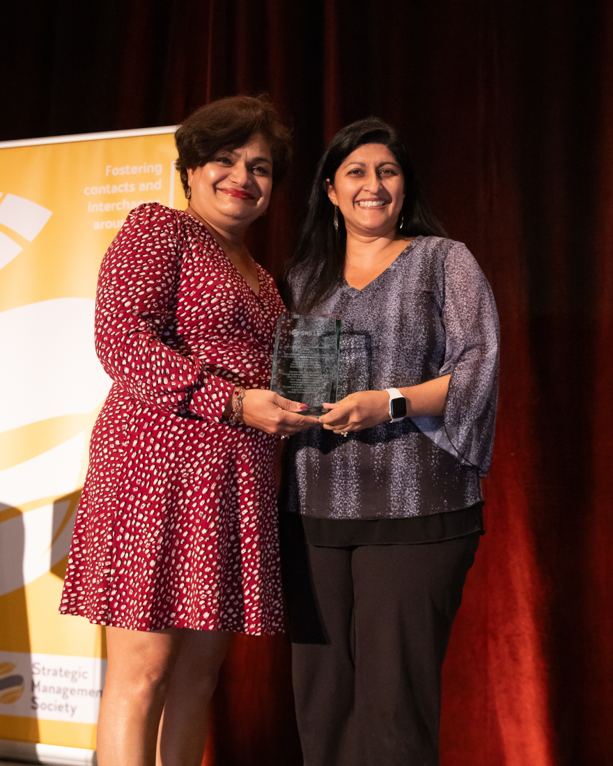 Professor Samina Karim accepts a glass award from professor Rajshree Agarwal.