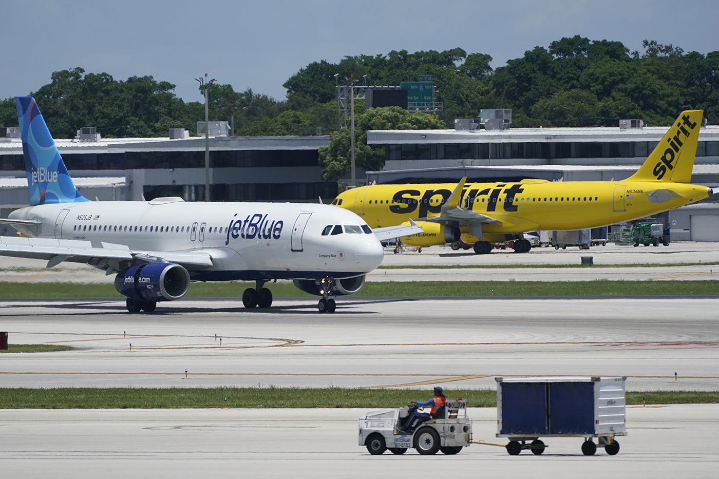 A JetBlue plane and a Spirit plane on different sections of a runway.