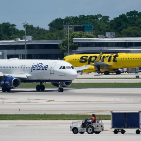 A JetBlue plane and a Spirit plane on different sections of a runway.