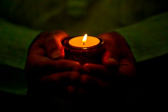 Person holding a tea candle to celebrate Diwali.