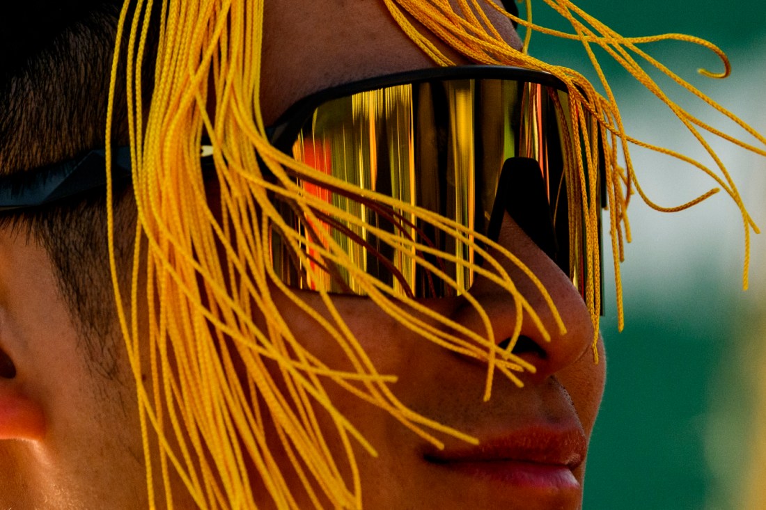 Person wearing yellow wrap-around sunglasses with their graduation cap tassel blowing in their face.