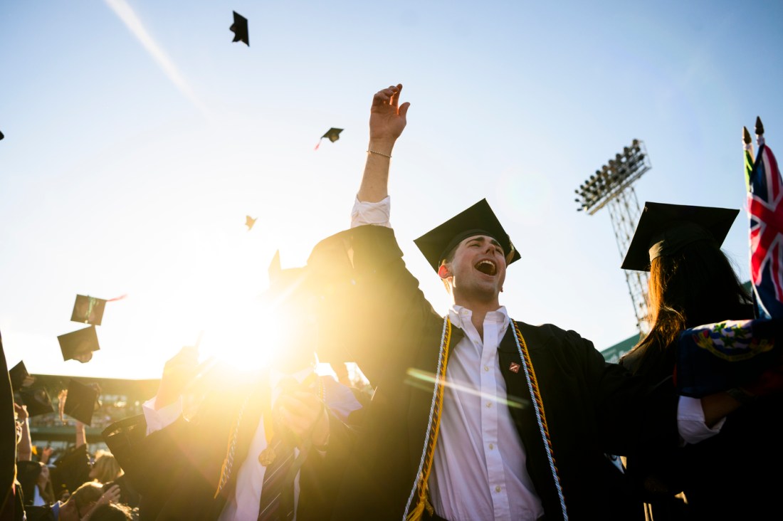 Northeastern community member cheering with their hand raised after graduating. 