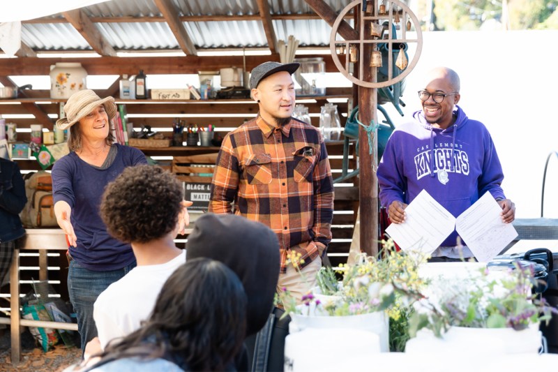 Mills Community Farm Manager Julia Dashe gesturing with her hands while standing next to two other people. 