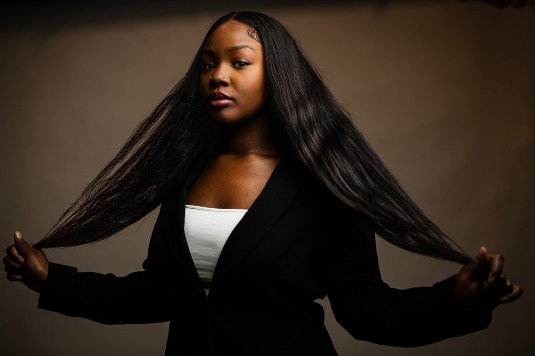 Head shot of Naomi Barrant, holding out long, dark hair.