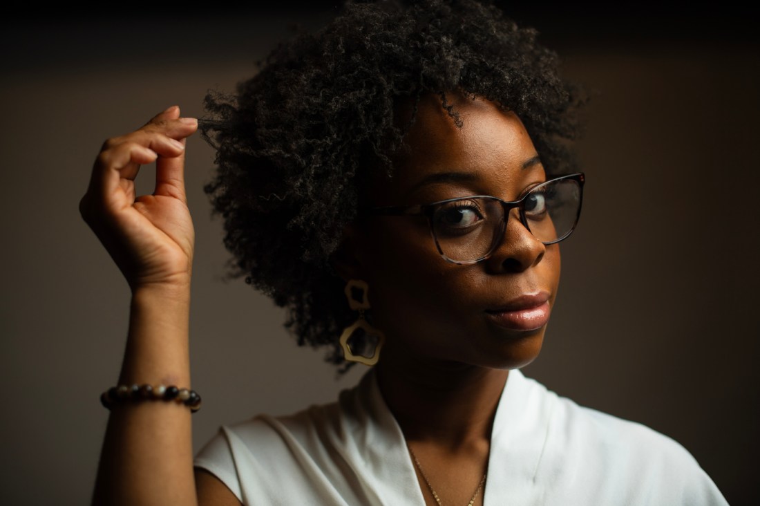 Head shot of Ashleigh Chiwaya, lightly pulling on a curl.