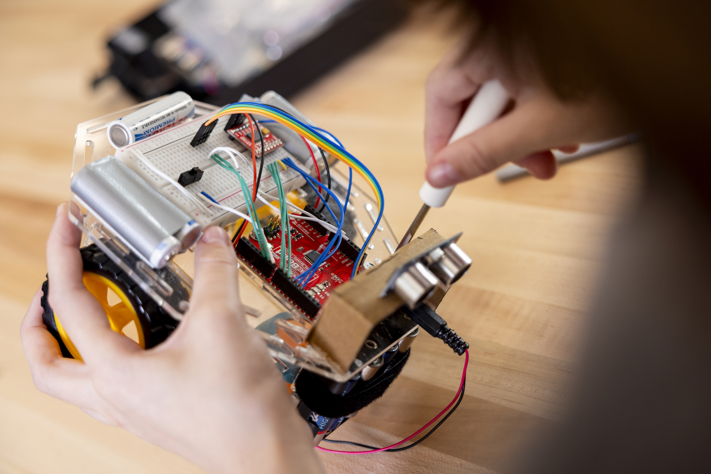 Student screwing a switchboard onto a robot.