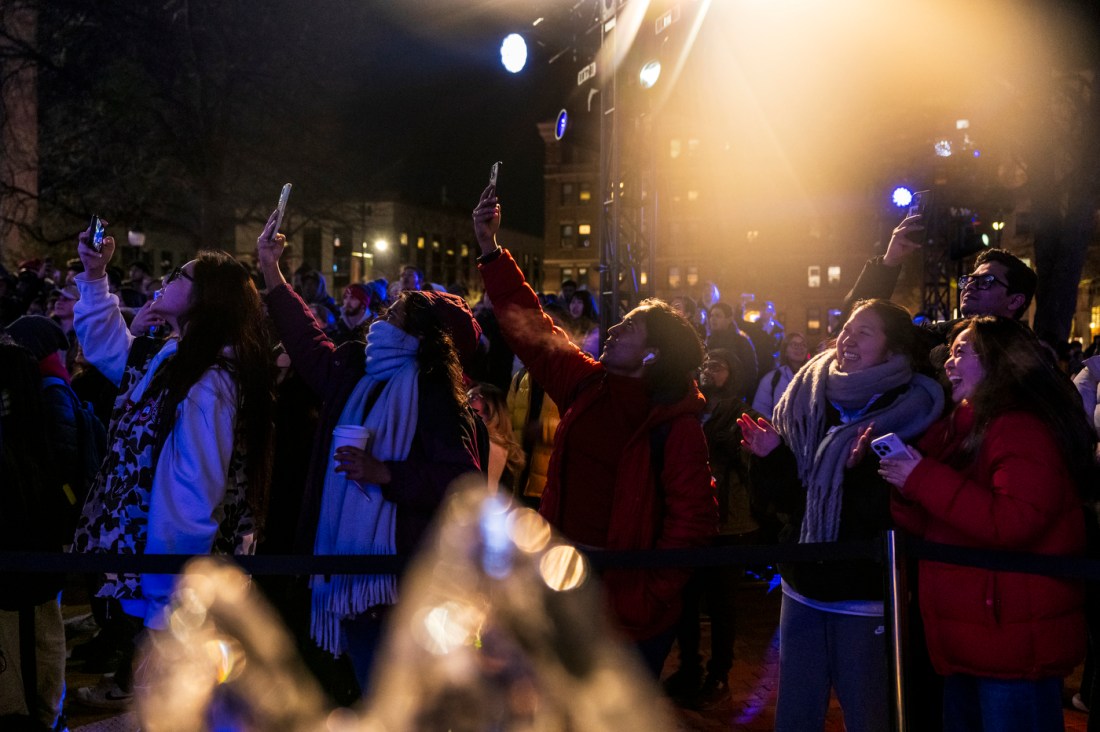 A group of people outside taking pictures with their phones.