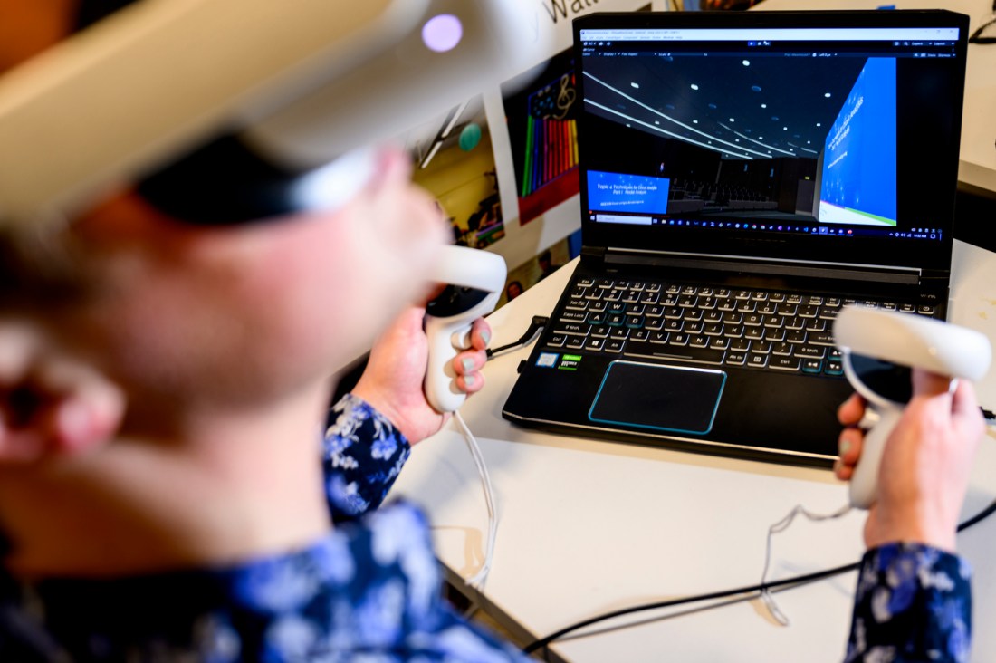 Student using VR goggles and hand held devices connected to a laptop.