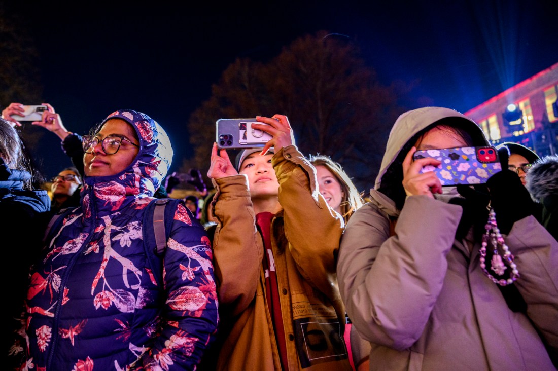 A group of people outside taking pictures with their phones.