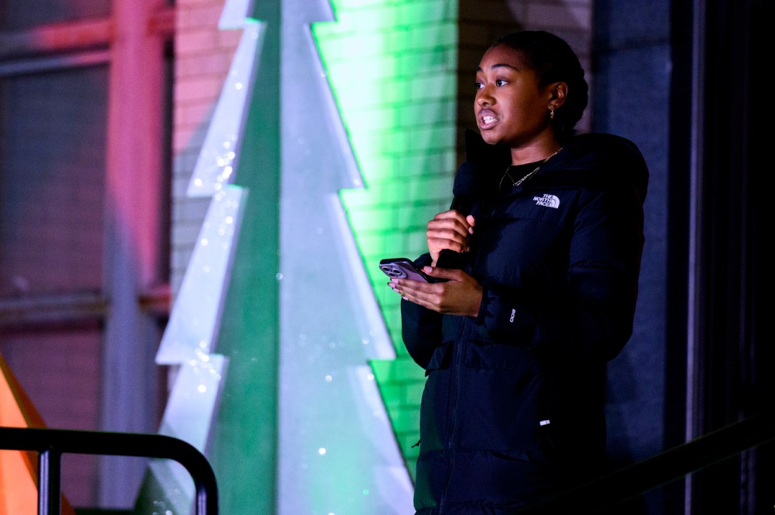 A person talks into a microphone outside Northeastern's Joy and Light Holiday Showcase.