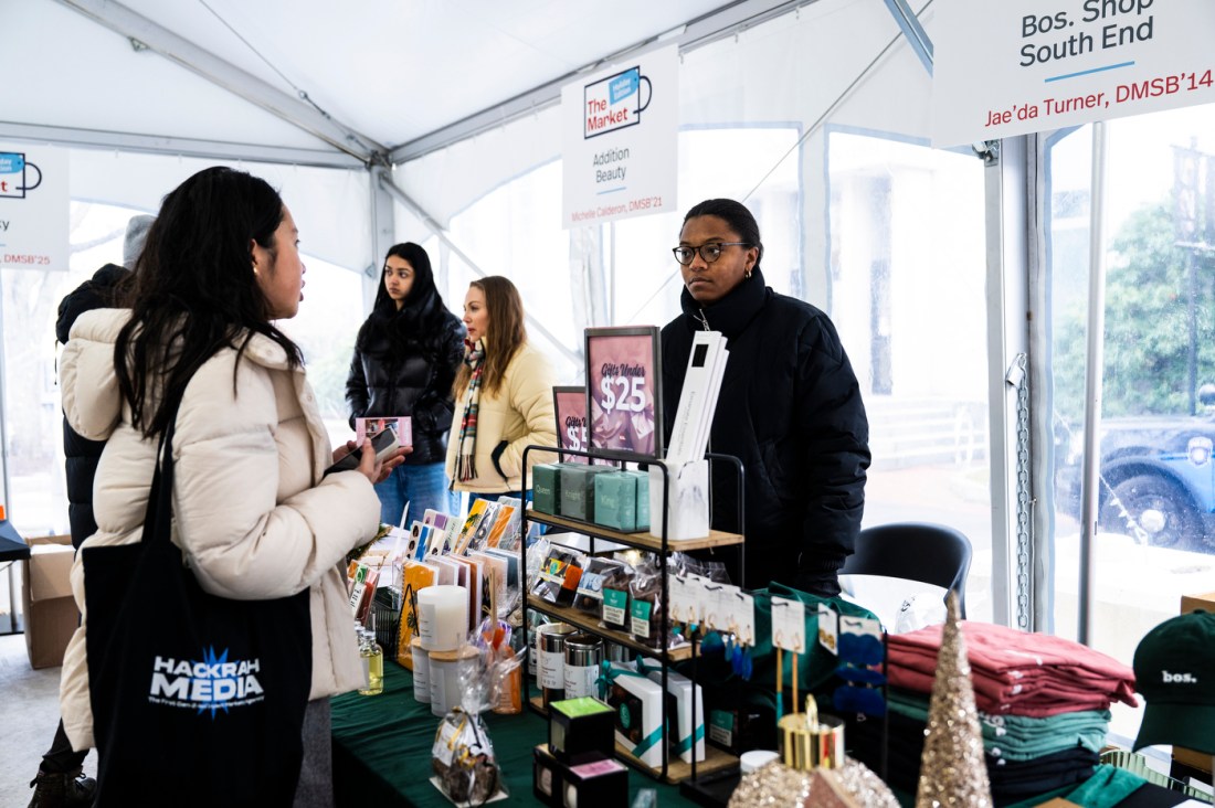 Northeastern entrepreneurs selling their goods at tables in a tent.