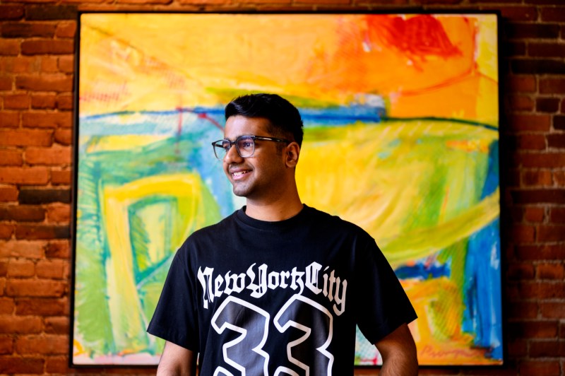 Harsh Shah posing in front of a large piece of art.