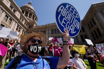 Abortion rights demonstrators outside of the Texas state capitol, one carrying a blue circular sign that says 'keep abortion legal' on it in white text