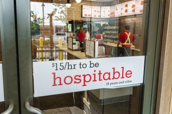 A sign on a Chick-fil-A door that says "$15/hr to be hospitable".