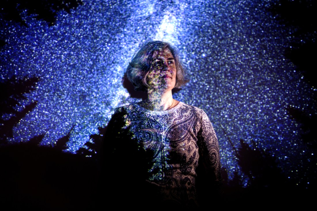 Headshot of a person with chin-length blonde hair and a starry night scene overlaid on top of her headshot. 