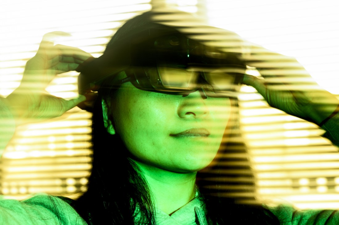 Northeastern community member putting on lab goggles in green lighting.