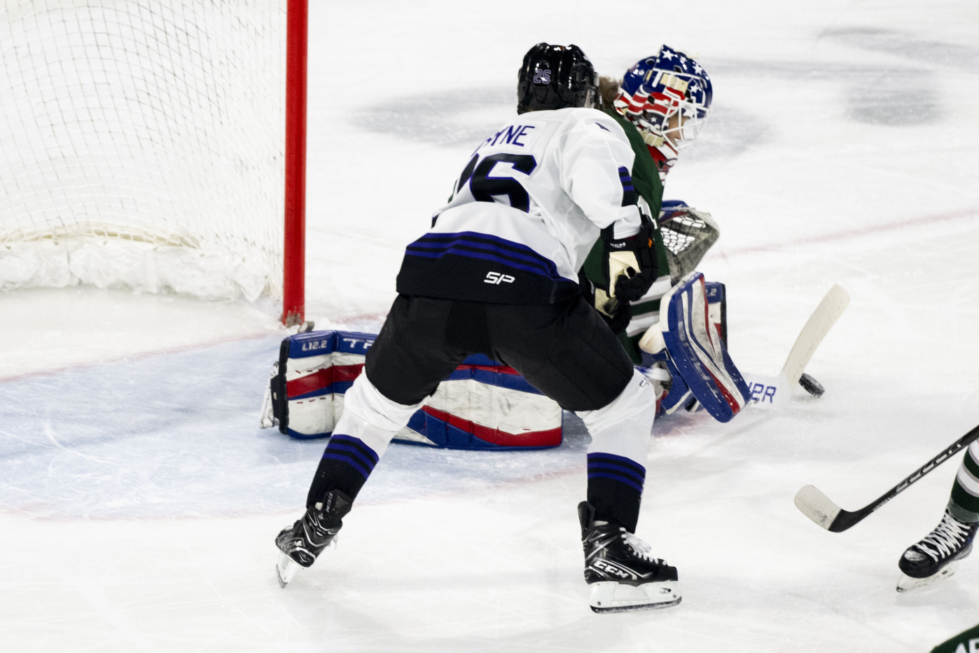 Two hockey players chase after the puck inside a hockey arena.