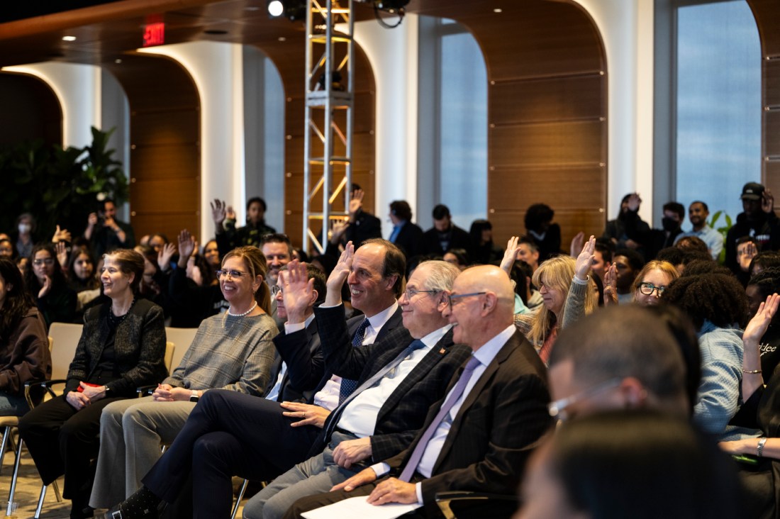 Several smiling attendees raise their hands.