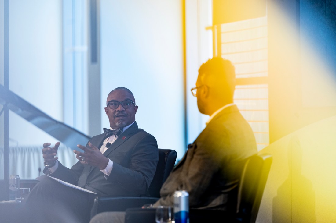 A bright, yellow light shines over two people talking on stage at Northeastern's MLK event.