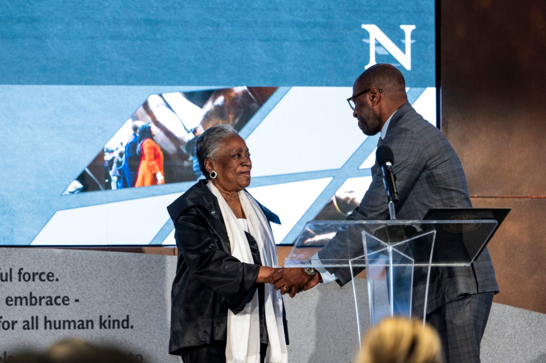 James R. Hackney shakes Charlotte M. Nelson's hands at the podium at Northeastern's MLK event.