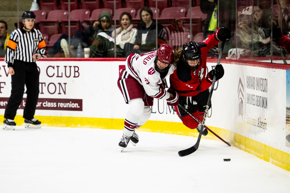 Two hockey players battle it out for a puck on the ice at the Women's Beanpot Semifinal.