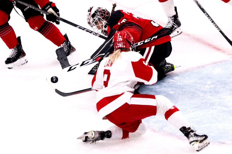 Northeastern women's hockey team goalkeeper saving a shot on the ice.