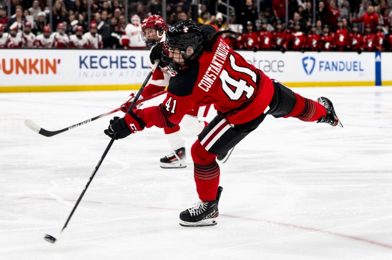 Northeastern women's hockey team member passing the puck.