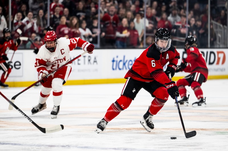 Northeastern women's hockey team skating with the puck.