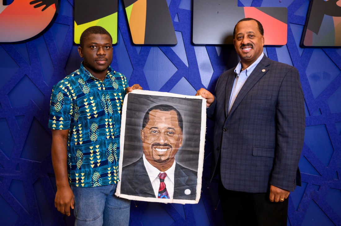 Richard L. O'Bryant and Moses Ayirebi holding up holding up a painting of Richard L. O'Bryant.