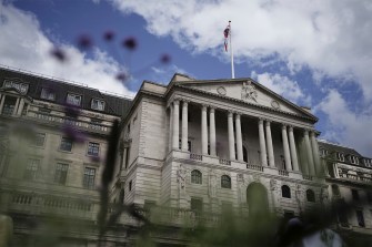 A large bank in London viewed outside on a slightly cloudy, blue sky day.