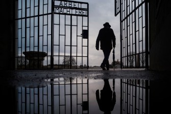 Silhouette of a man walking through the gate of a Nazi death camp in Germany.